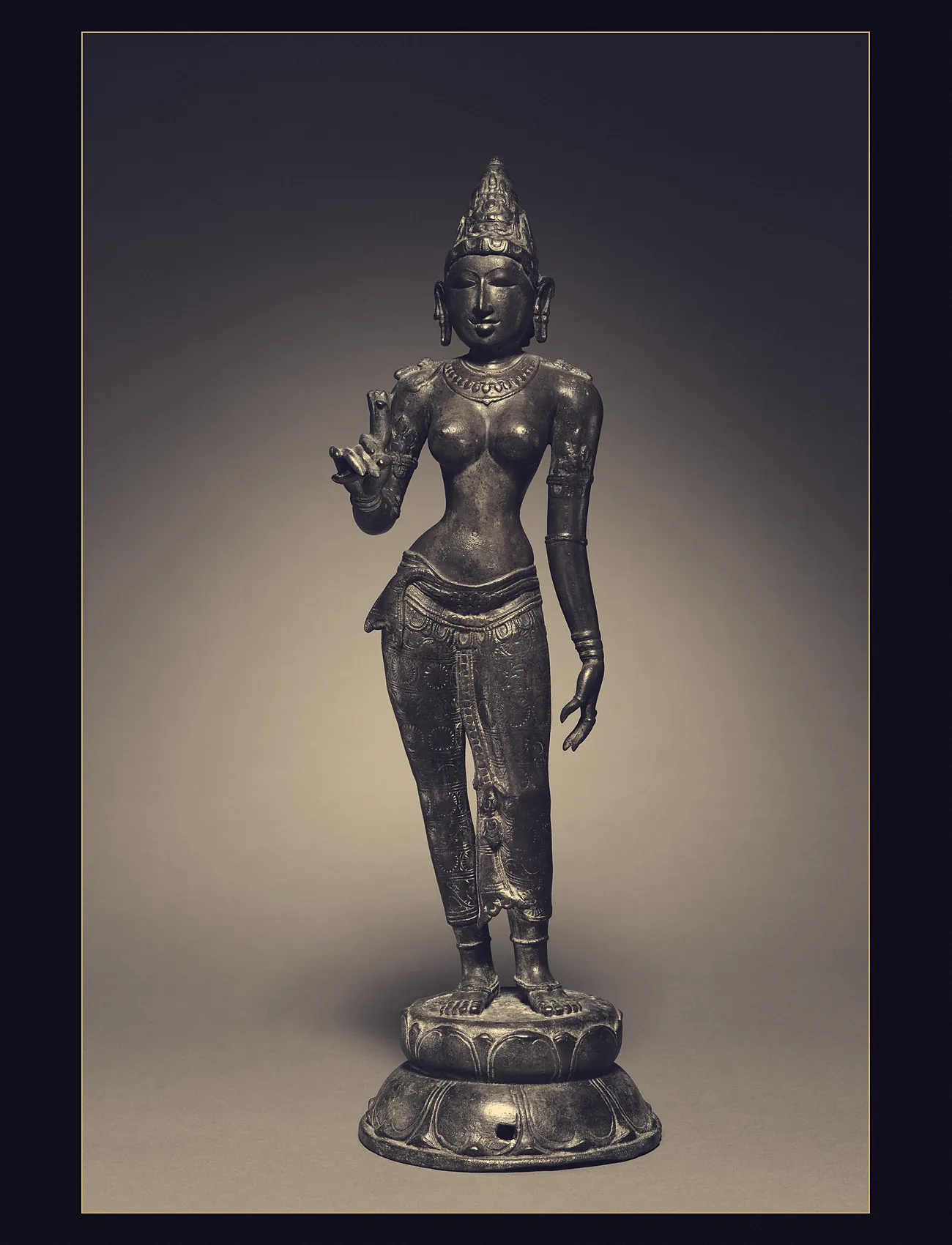 A Chola bronze of a standing goddess on a double lotus, holding a lotus in her raised hand