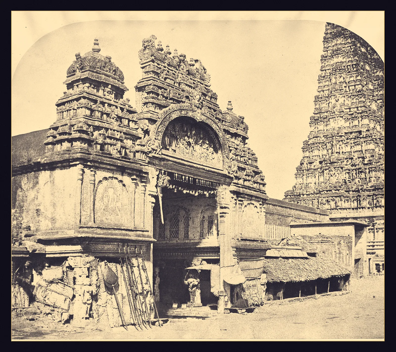An 1858 photograph of a South Indian temple entrance, a dark doorway under a carved arch with a tall gopura rising behind