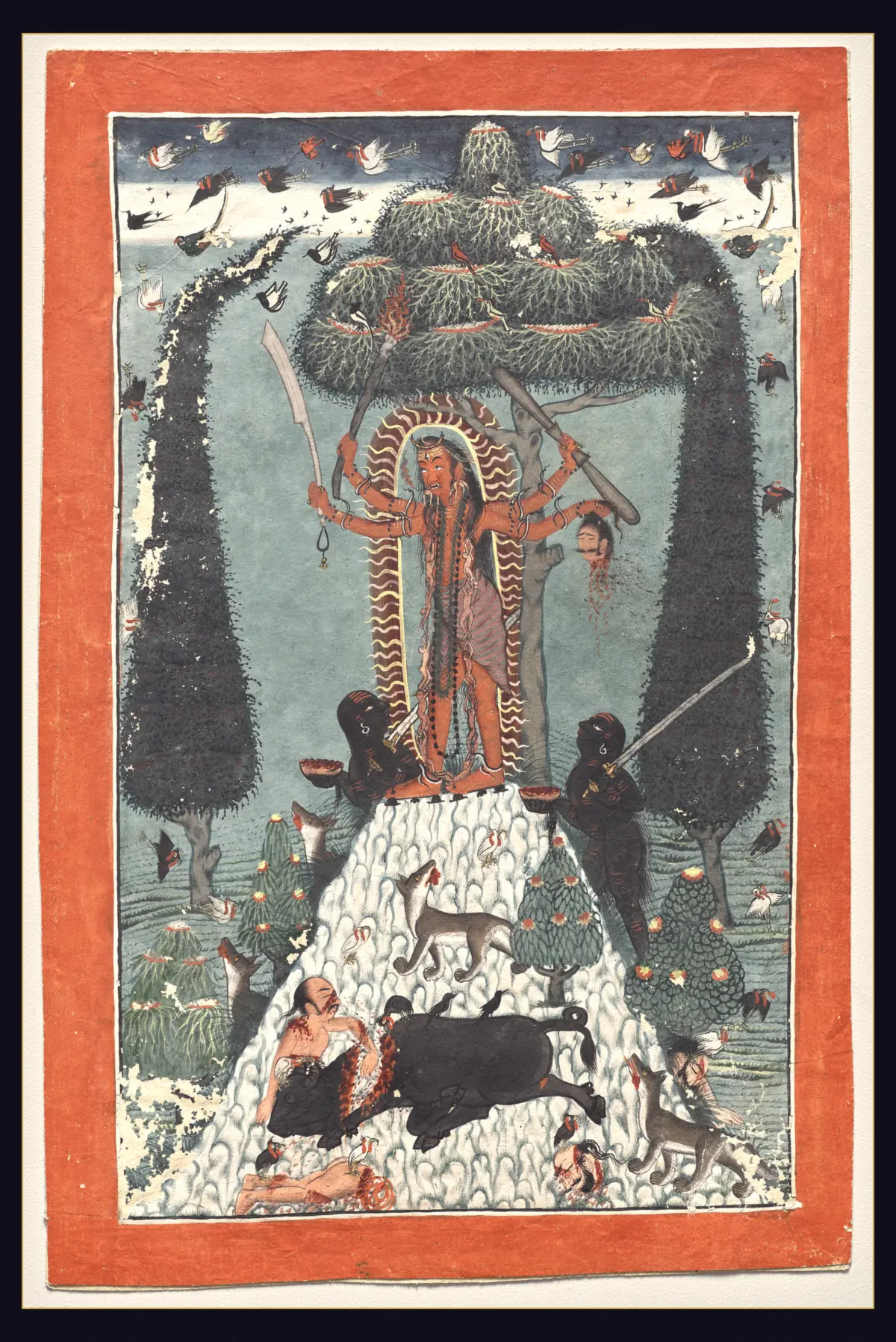 A Pahari painting of a fanged four-armed goddess with long matted hair standing on a white mountaintop under a large tree, inside a red halo edged with flames, holding a flaming torch, a sword with a looped cord hanging from it, a club and a dripping severed head, with two dark attendants offering bowls of blood and jackals, birds and a slain buffalo below.