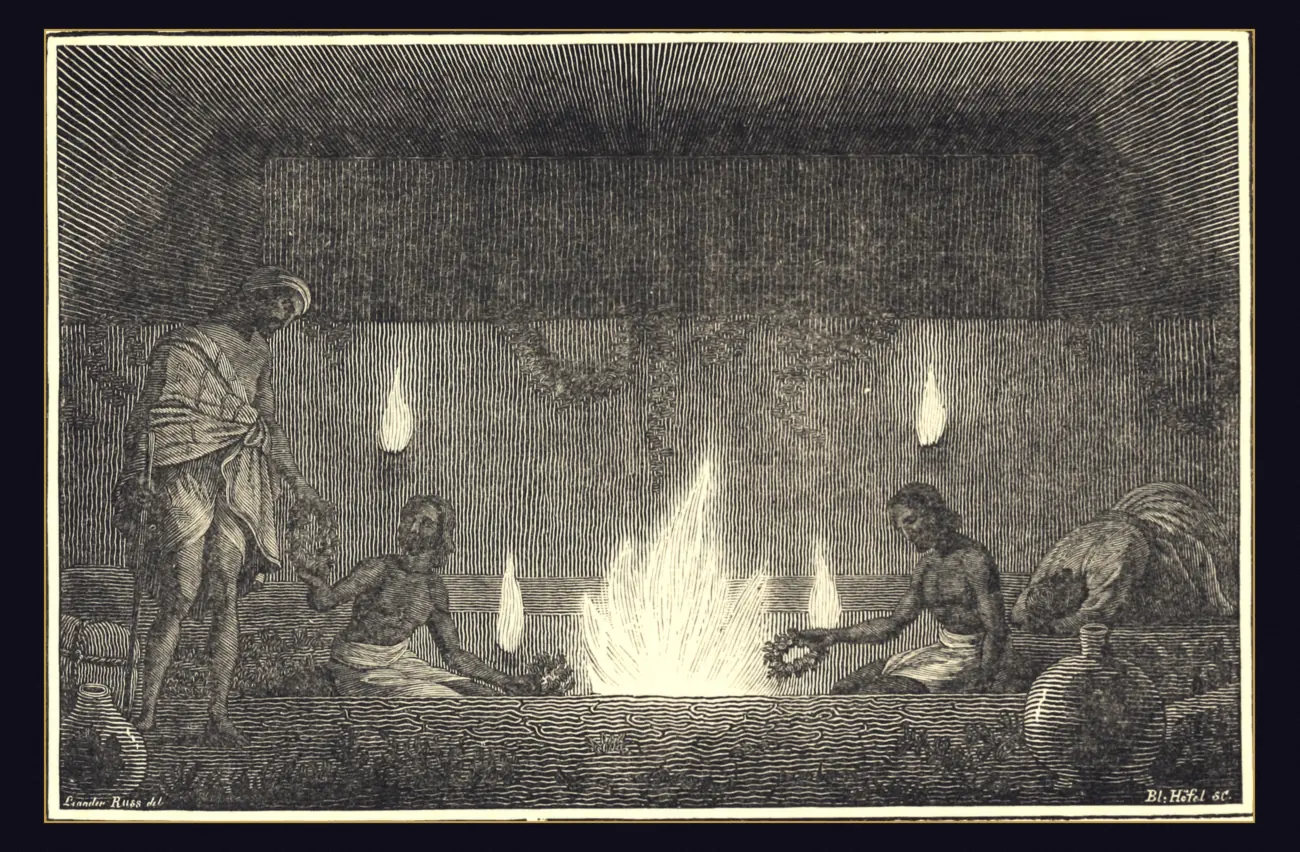 A nineteenth century wood engraving of a stone temple court with a large flame rising from a long pit in the floor, two ascetics seated at either end of the pit holding garlands to the fire, smaller flames burning out of the rock wall behind them, a pilgrim standing on the left and pots on the floor.